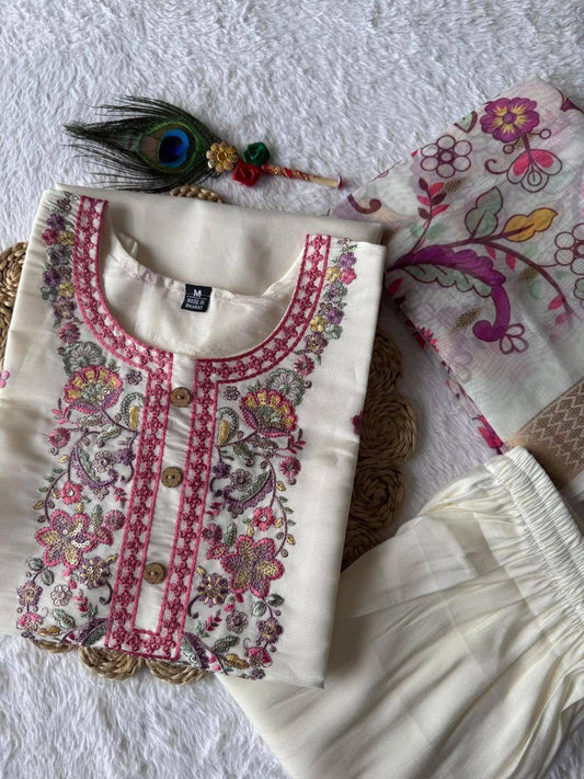 Embroidered white outfit with floral patterns on a textured surface